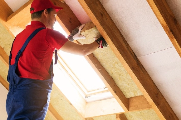 Person befestigt Dämmwolle am Dach.